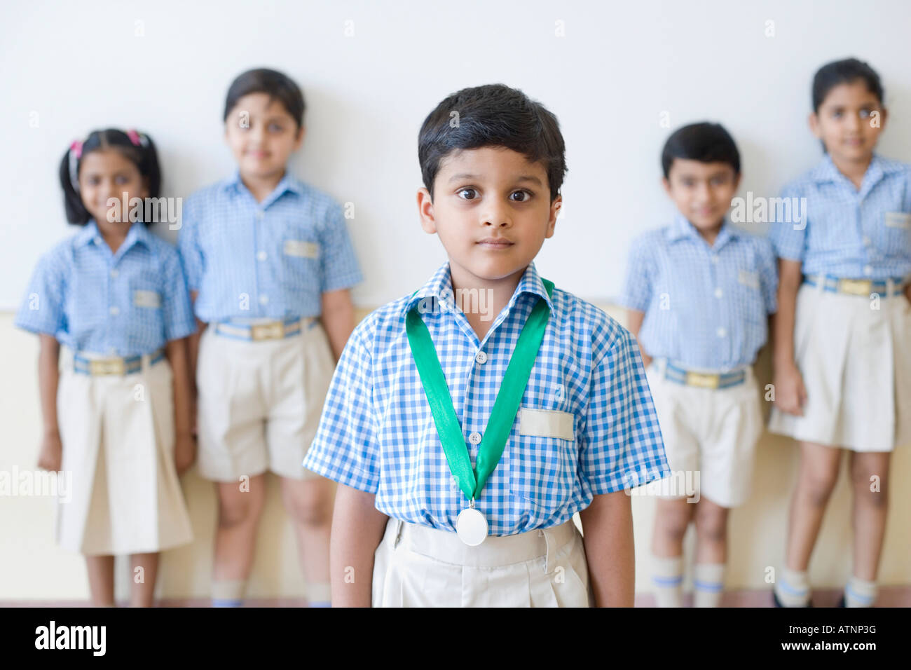 Porträt von Schuljunge mit einer Medaille um den Hals mit seinen Mitschülern im Hintergrund Stockfoto