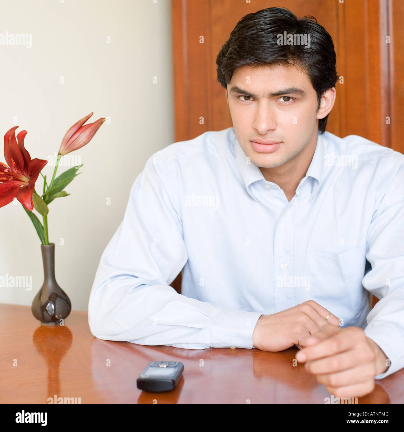Porträt eines jungen Mannes, der an einem Tisch sitzen Stockfoto