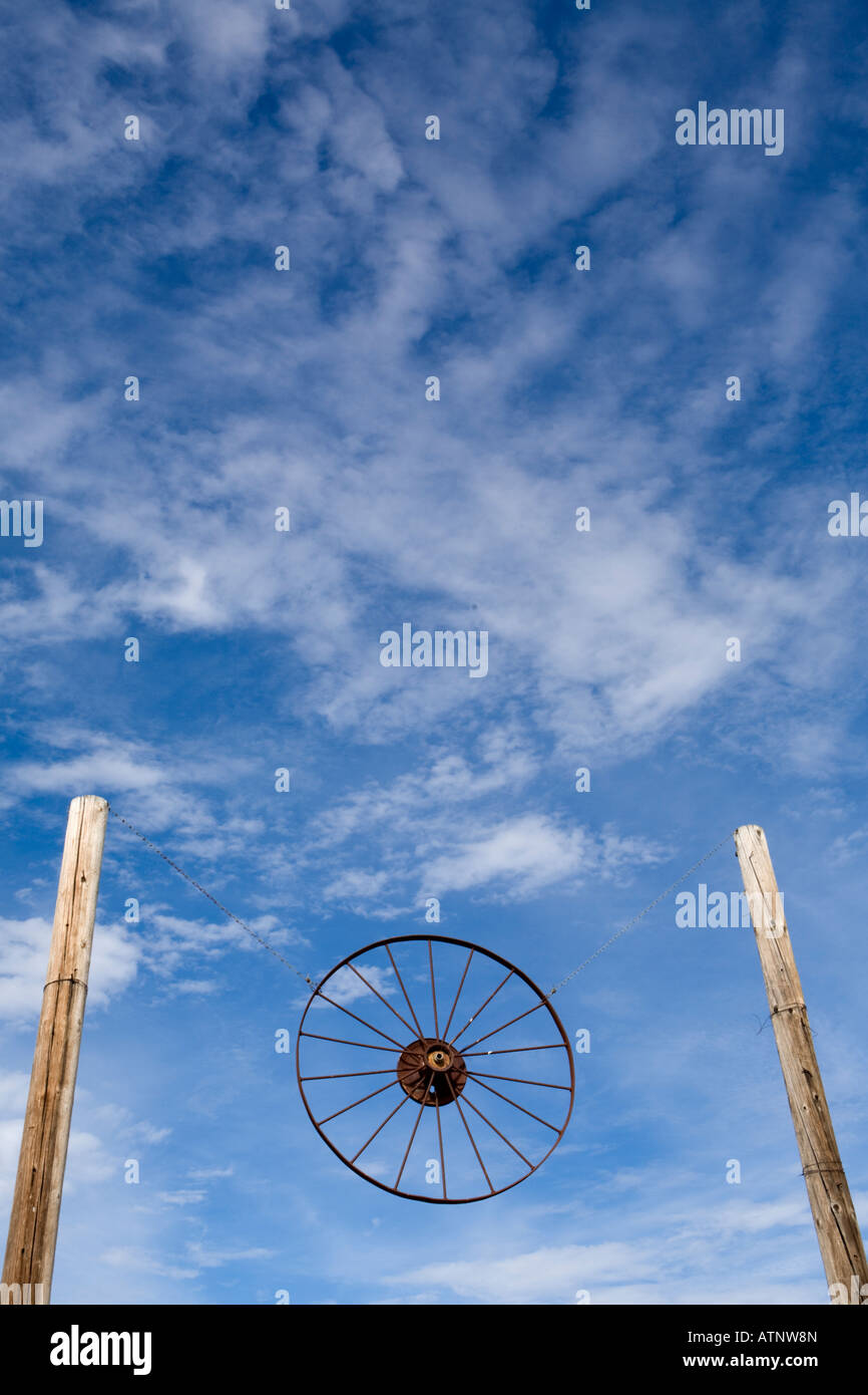 Eine westliche Wagenrad schwebt zwischen zwei Polen vor einem tiefblauen Himmel. Stockfoto