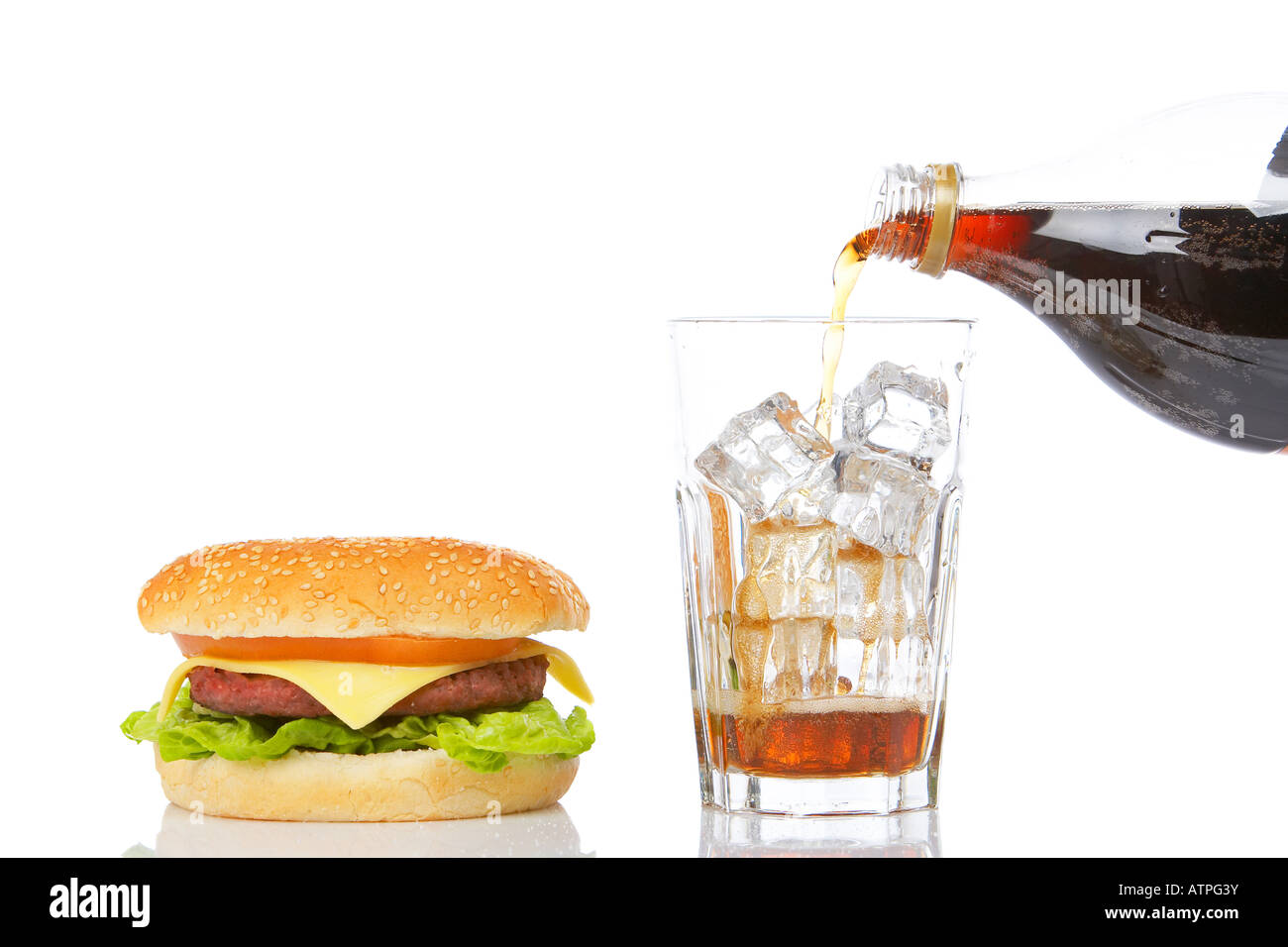 Cheeseburger mit Salat und Tomate und gießen Natron in ein Glas mit Eiswürfeln reflektiert auf weißem Hintergrund Stockfoto