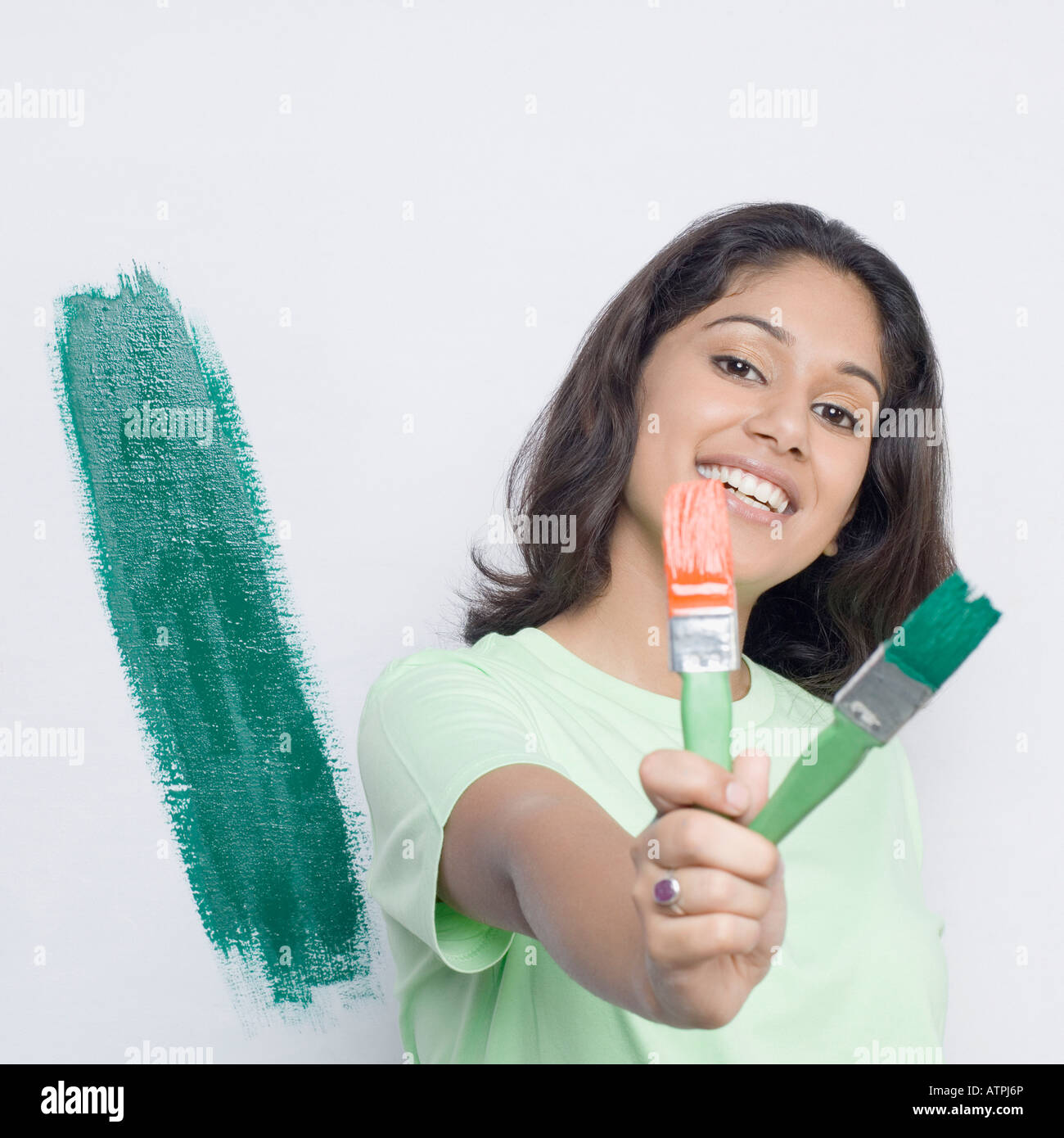 Porträt einer jungen Frau zeigt zwei Pinsel und lächelnd Stockfoto