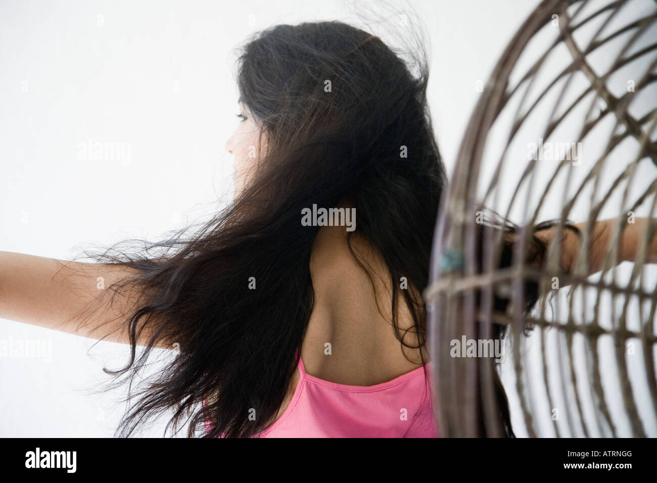 Rückansicht einer jungen Frau mit ihrem Arm ausgestreckt vor einem Ventilator Stockfoto