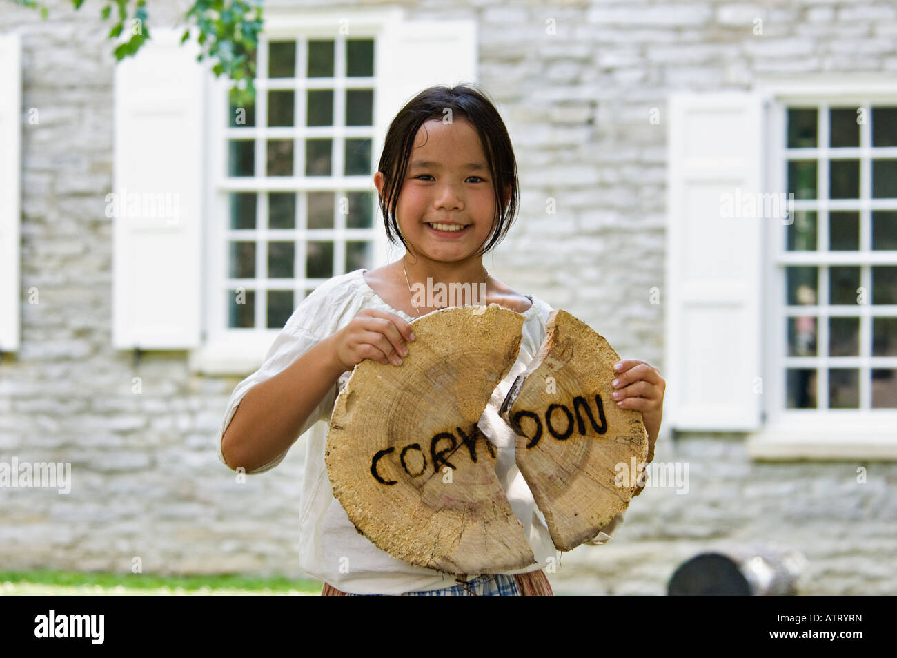 Junge asiatische Mädchen Holding Stück der gesägt Log mit the Stadt Name von Corydon gebrandmarkt drin während Indiana-Territorium-Festival Stockfoto