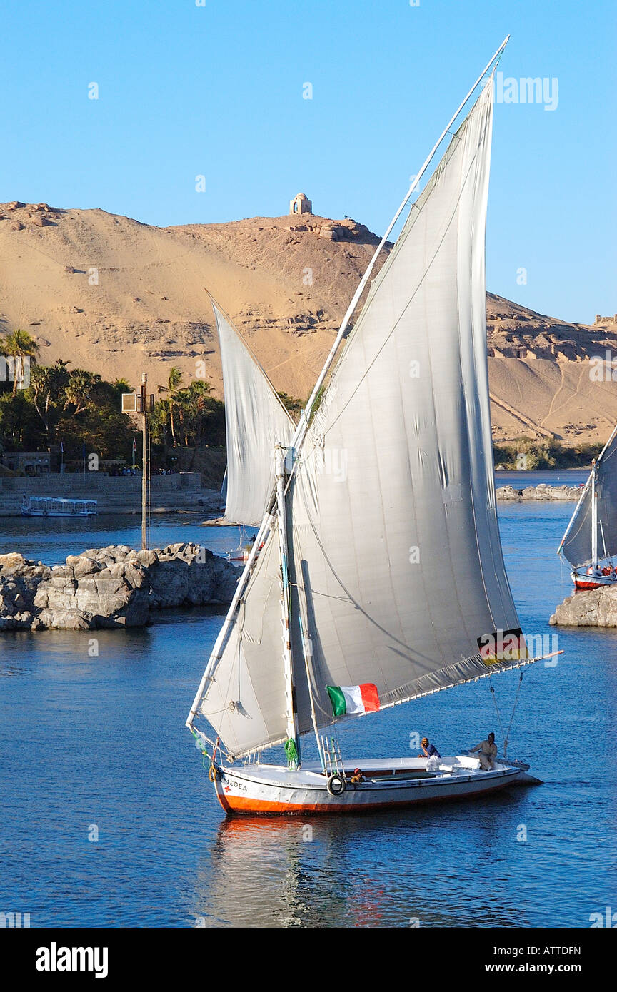 Feluccas, traditionellen Holz- segeln Boote auf dem Nil in Assuan, Ägypten mit Aga Khan Mausoleum im Hintergrund Stockfoto