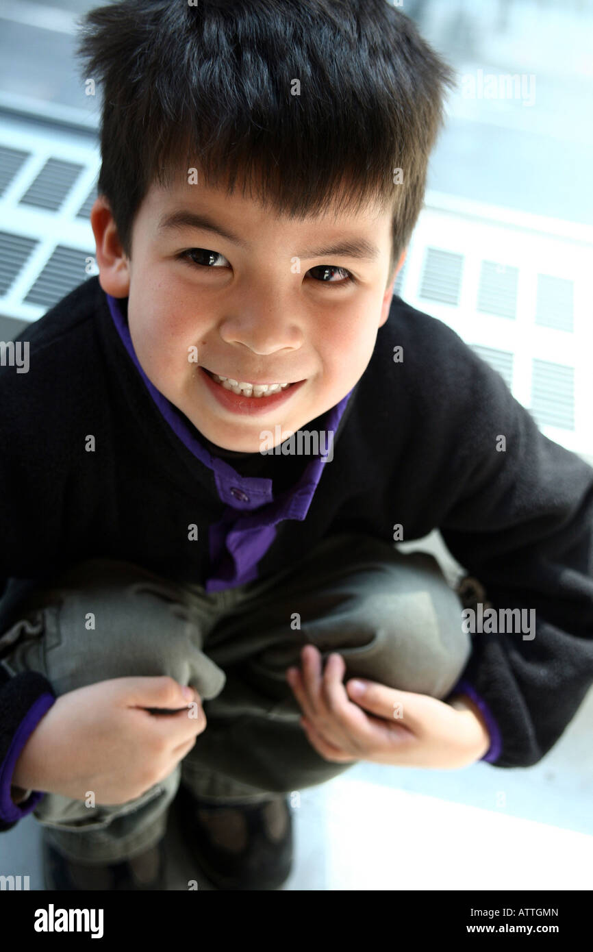 Niedlicher kleine Junge posiert mit großen Lächeln, beim sitzen und die Knien halten.  Foto von Tom Zuback Stockfoto