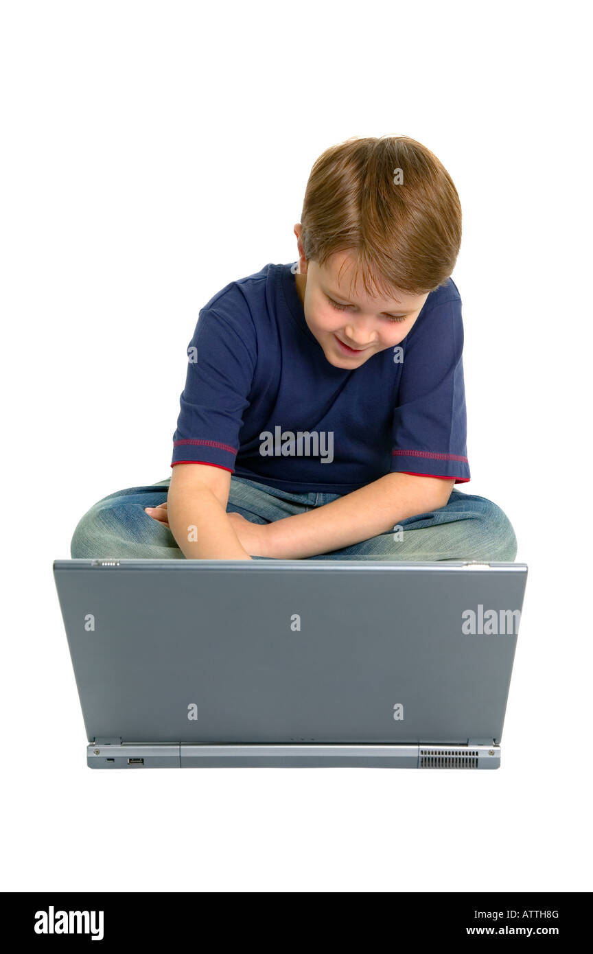 Glückliche junge Junge saß mit einem Laptop isoliert auf weißem Stockfoto