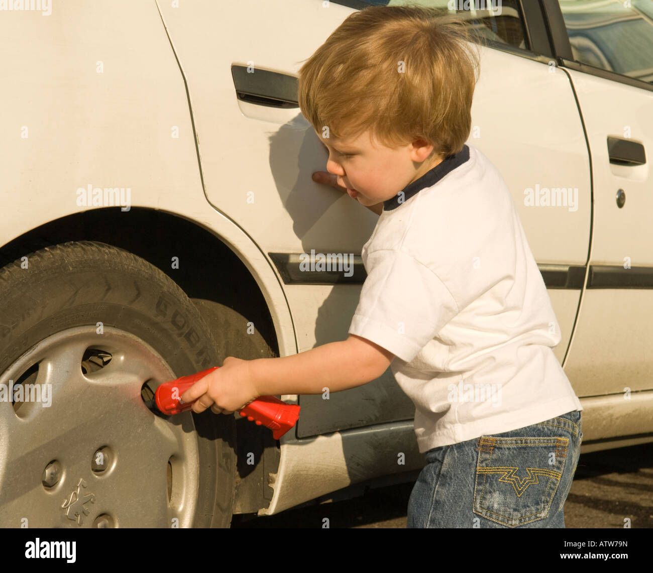 zwei Jahre alter Junge mit Spielzeug Bohrer als Mechaniker arbeitet an einem Auto spielen Stockfoto