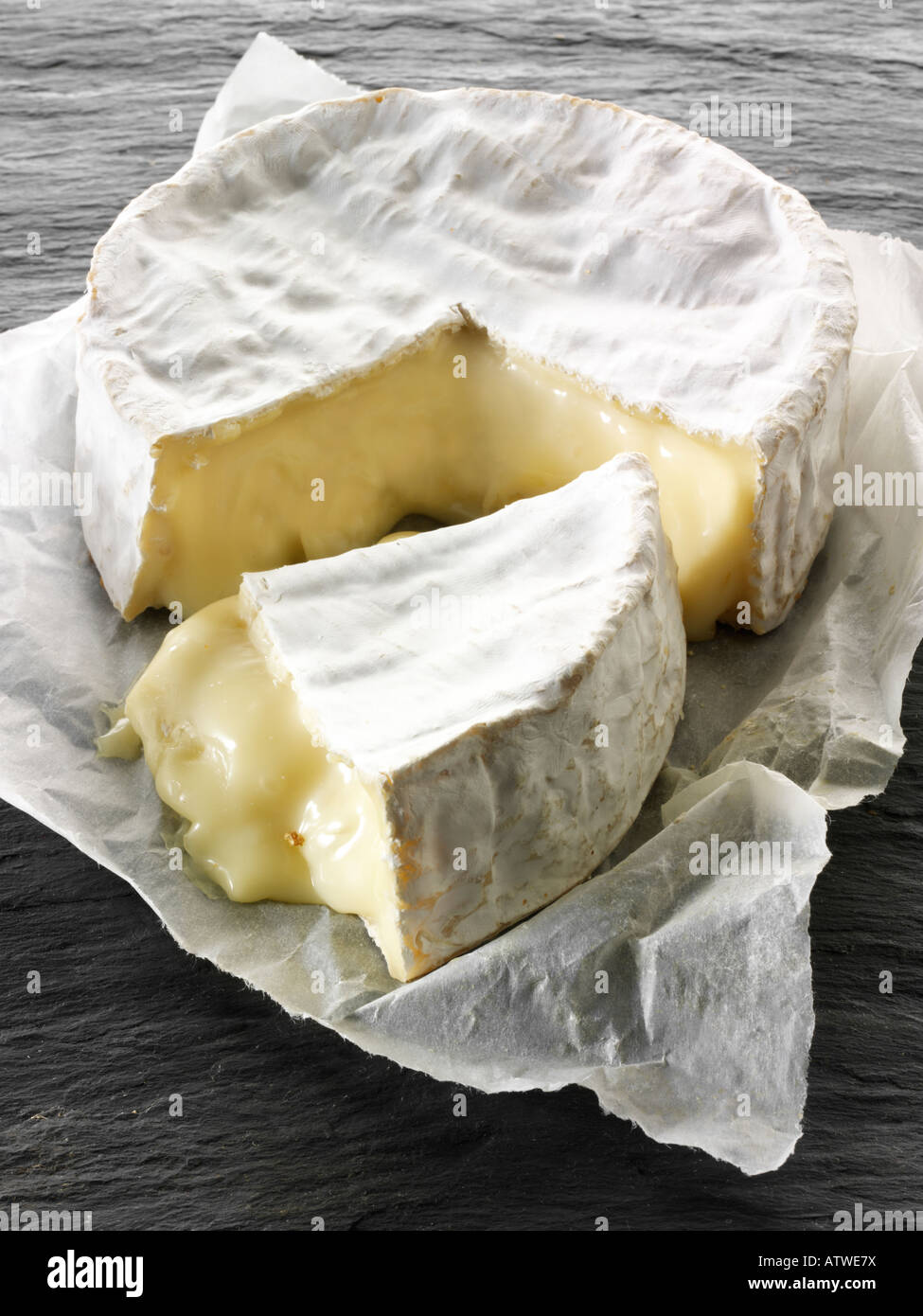 Camembert schneiden vor schwarzem Hintergrund Stockfoto
