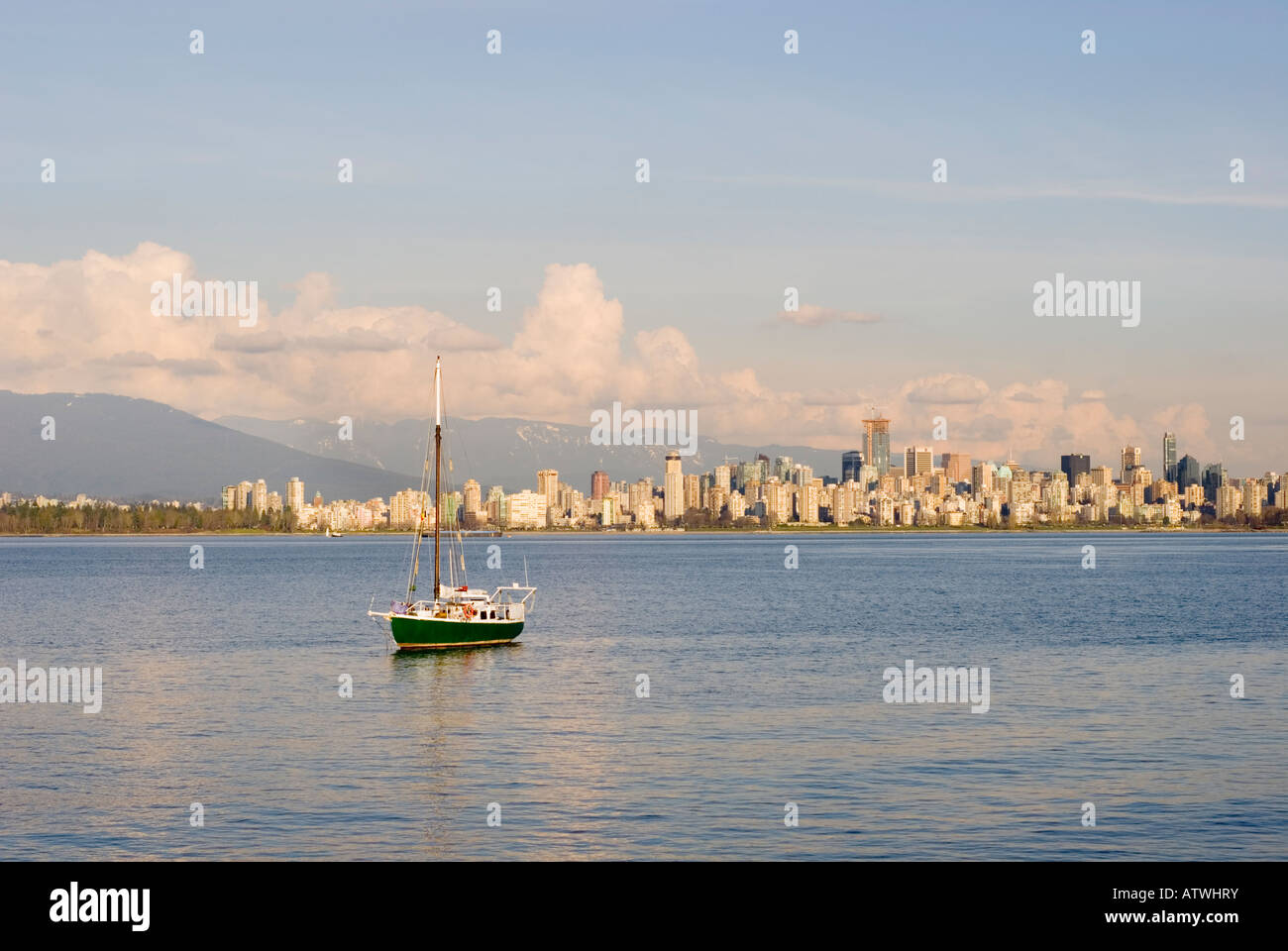 Ein einsamer Segelboot sitzt vor Anker im Burrard Inlet mit der Skyline von Vancouver Kanada in der Ferne Stockfoto