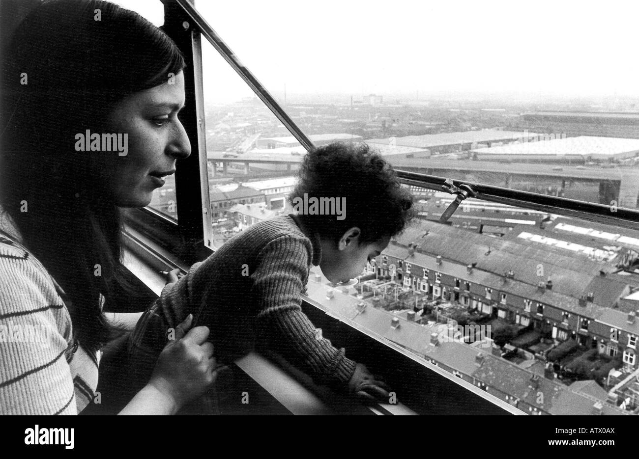Junge alleinerziehende Mutter mit ihrem Kleinkind in Birmingham Hochhaus mit Blick auf Autobahnkreuz Leben. Stockfoto
