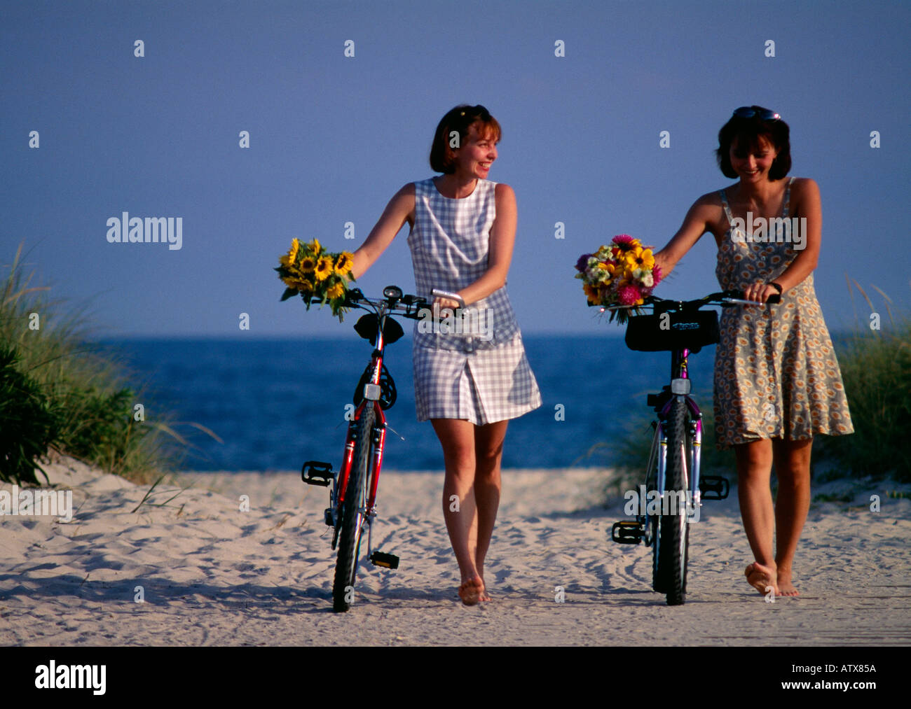 Zwei junge Frauen sitzen auf dem Fahrrad mit Korb mit Blumen Stockfoto