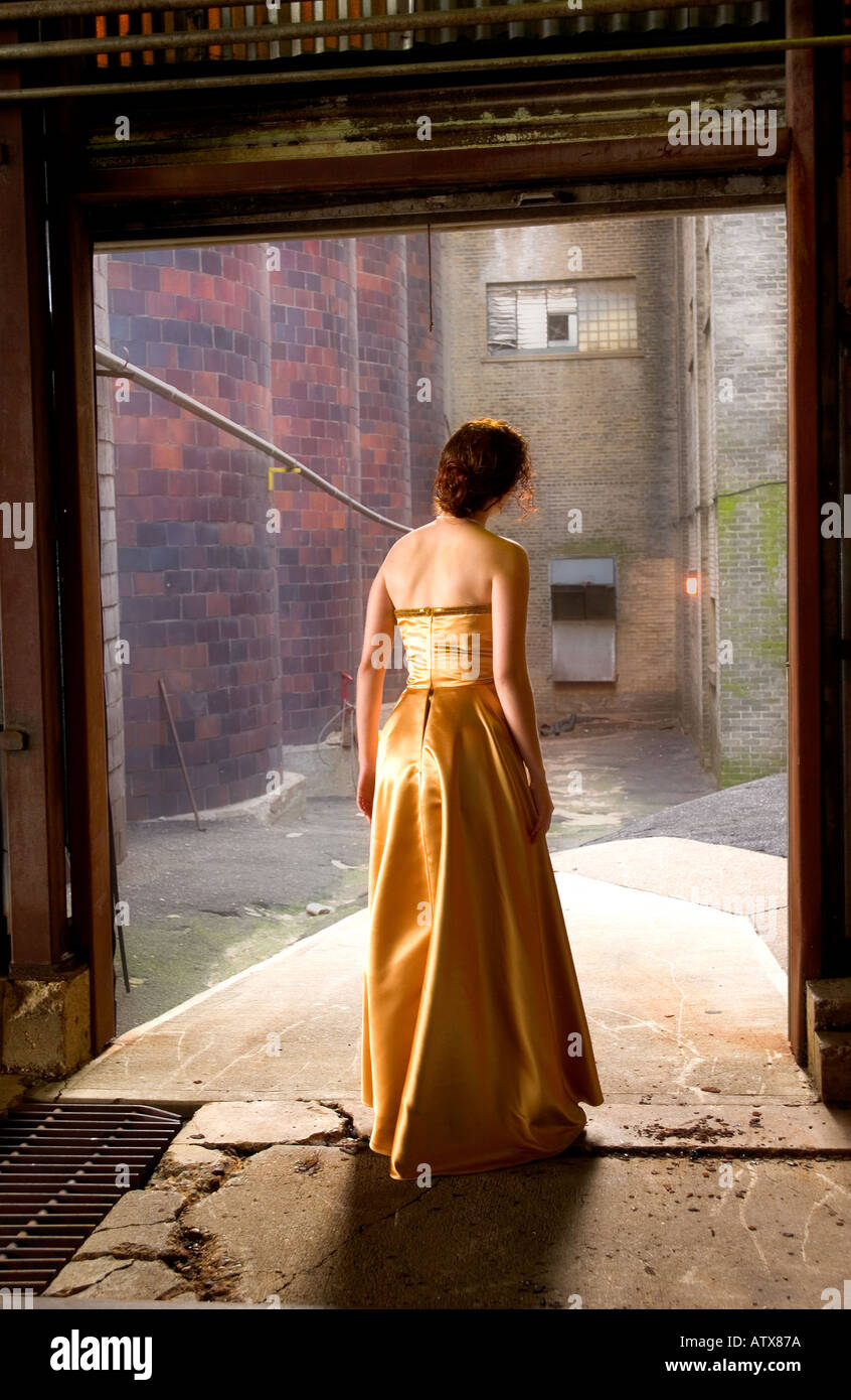 Mädchen im goldenen Kleid aus einem Industriegebiet Stockfoto