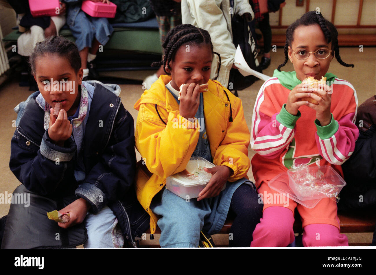 drei Mädchen sitzen essen ihre Lunchpakete. Stockfoto