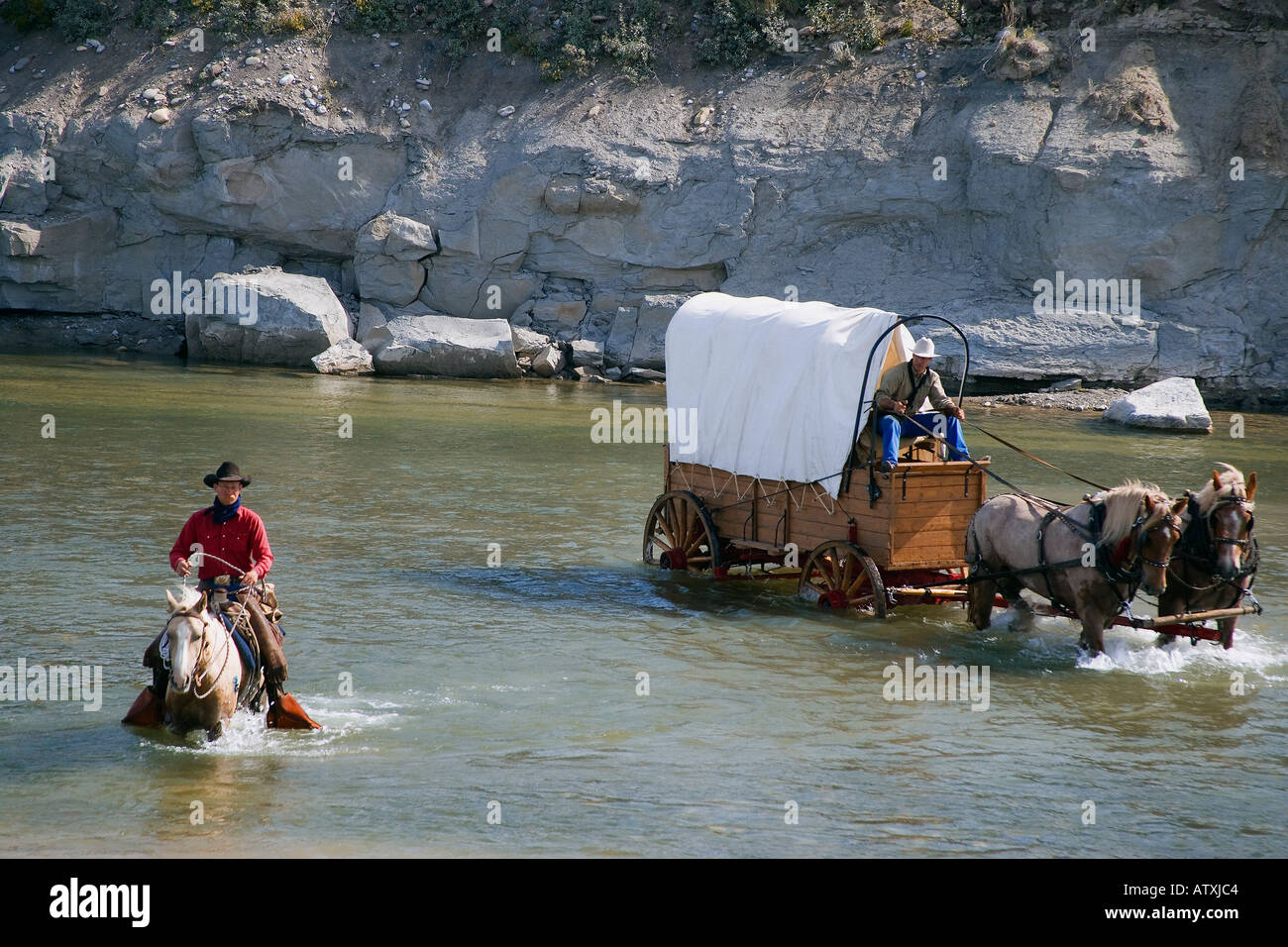 Cowboys und einem Planwagen Überquerung eines Flusses Stockfoto