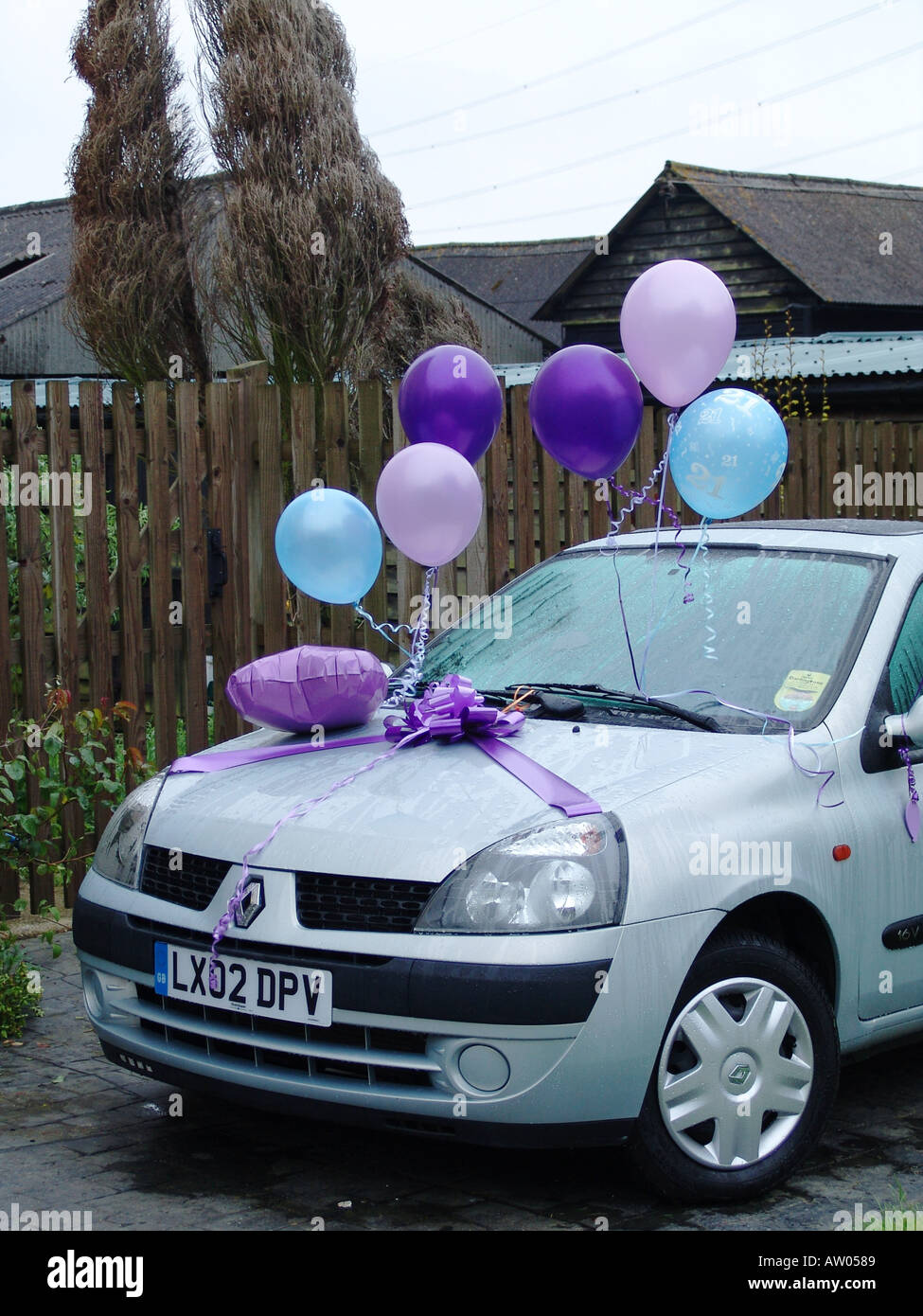 Weißes Renault Clio Auto mit lila und blauen Ballons und Schleife als Geburtstagsgeschenk, Großbritannien Stockfoto
