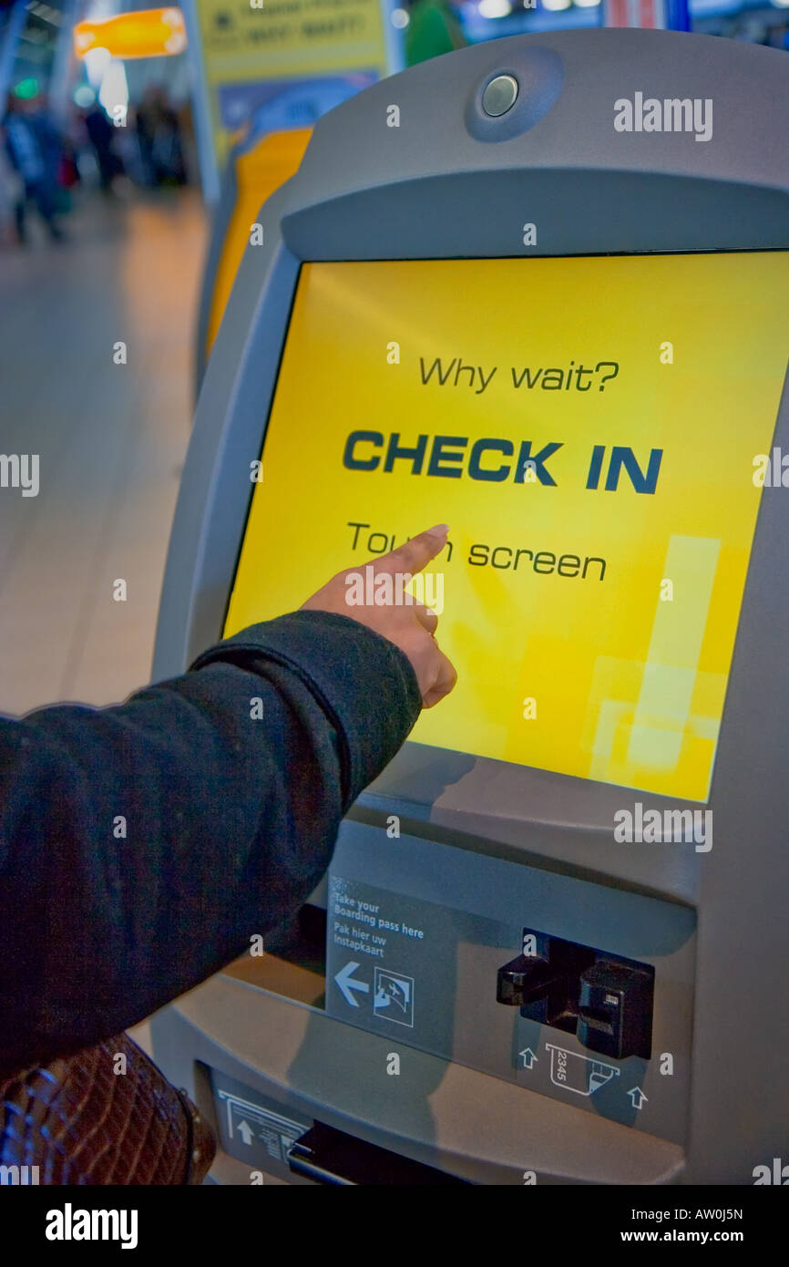 Frau mit dem Selbsttest im Terminal mit sensiblen Touchscreen auf Shiphol Airport, Niederlande Stockfoto