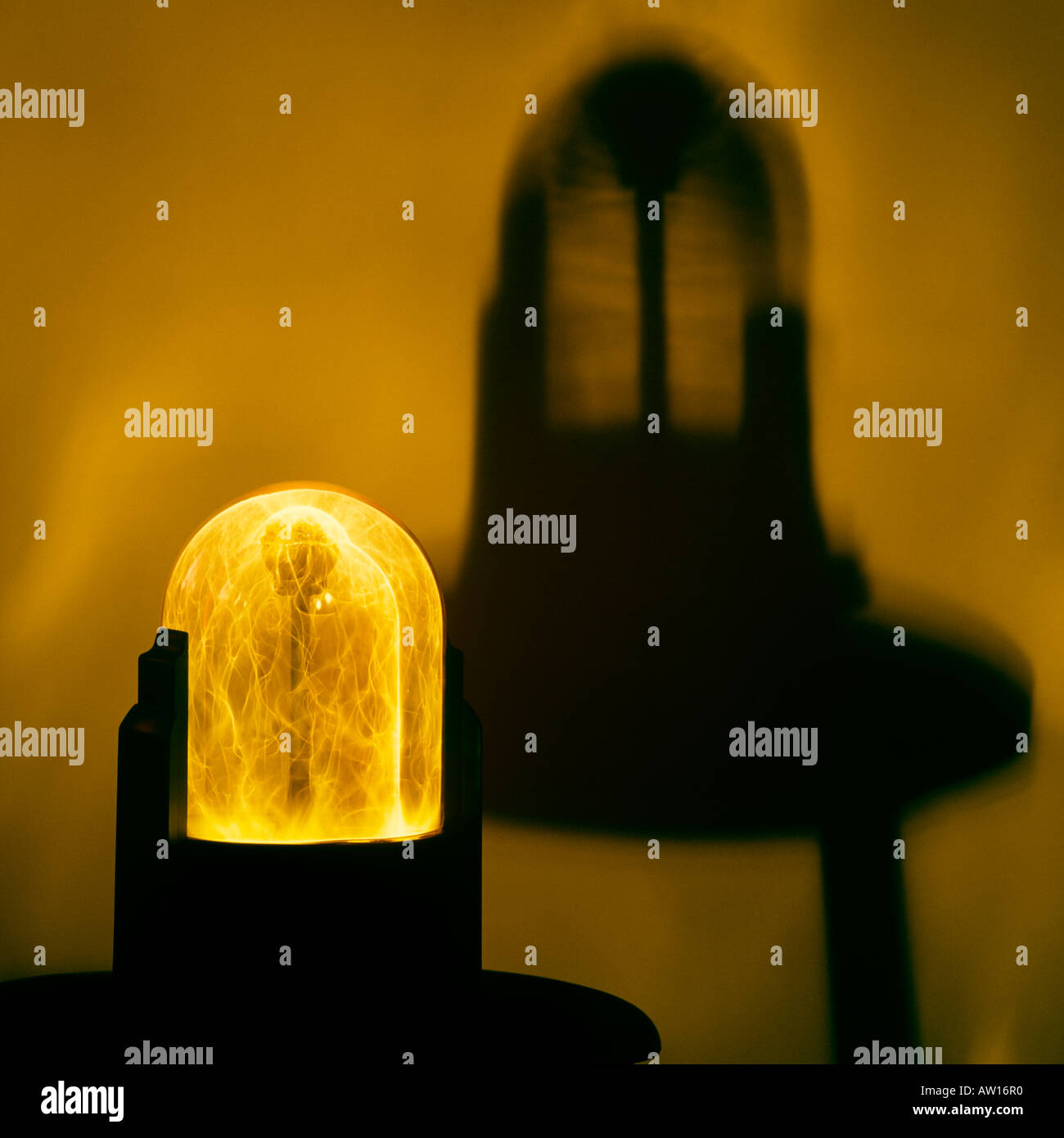 Eine Plasmakugel sendet elektrische Ströme vor einem dramatischen gelben Hintergrund. Eine dunkle schwarze Schatten ist vor dem Hintergrund. Stockfoto