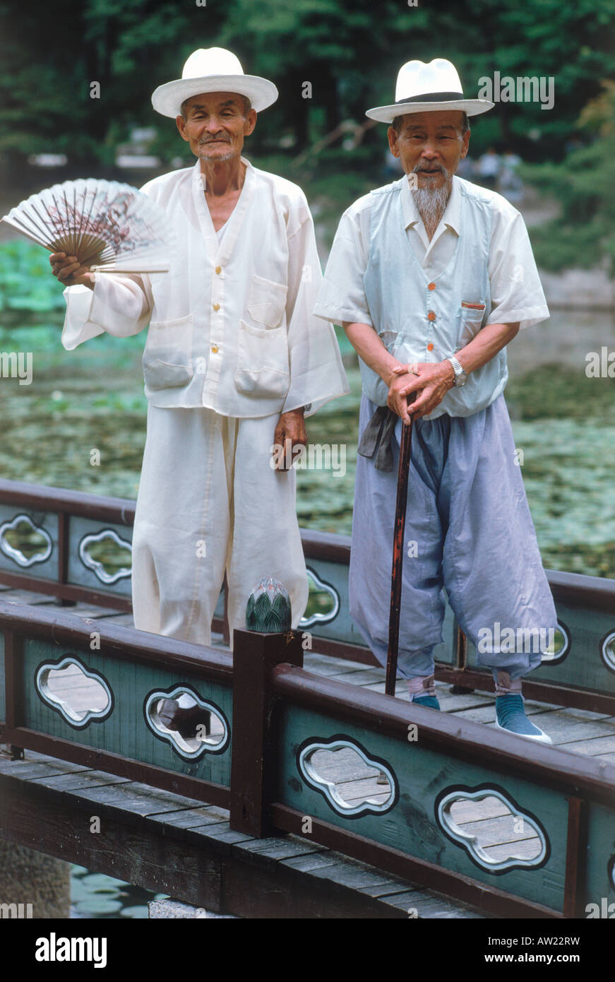 Zwei ältere Männer in leichten Leinen-Outfits mit Hüten und Hand statt Ventilatoren für heiße Sommertage in Südkorea Stockfoto