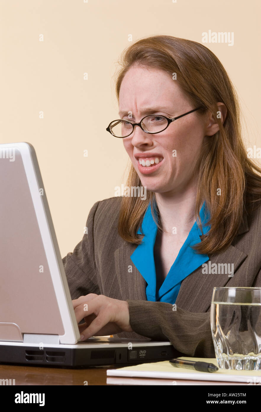 eine junge Geschäftsfrau Grimassen auf was sie auf ihrem Laptop-Computer-Bildschirm sieht Stockfoto