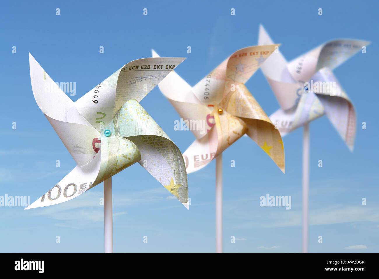 Drei Spielzeug Windmühlen Schnitt von 100, 50 und 20-Euro-Banknoten über blauen Himmel Stockfoto