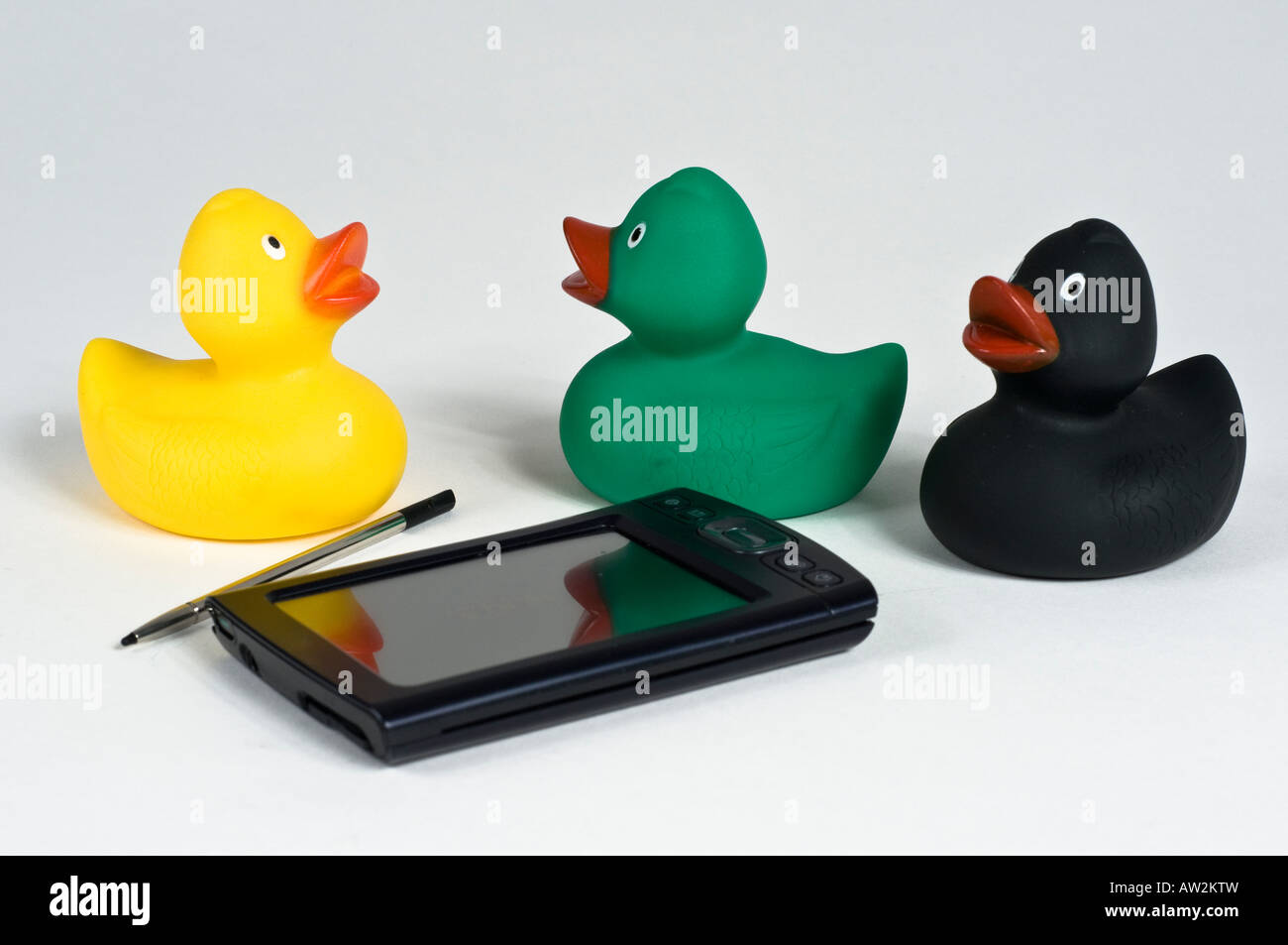 3 farbige Spielzeug Enten sitzen um einen Pda mit Stift Stockfoto