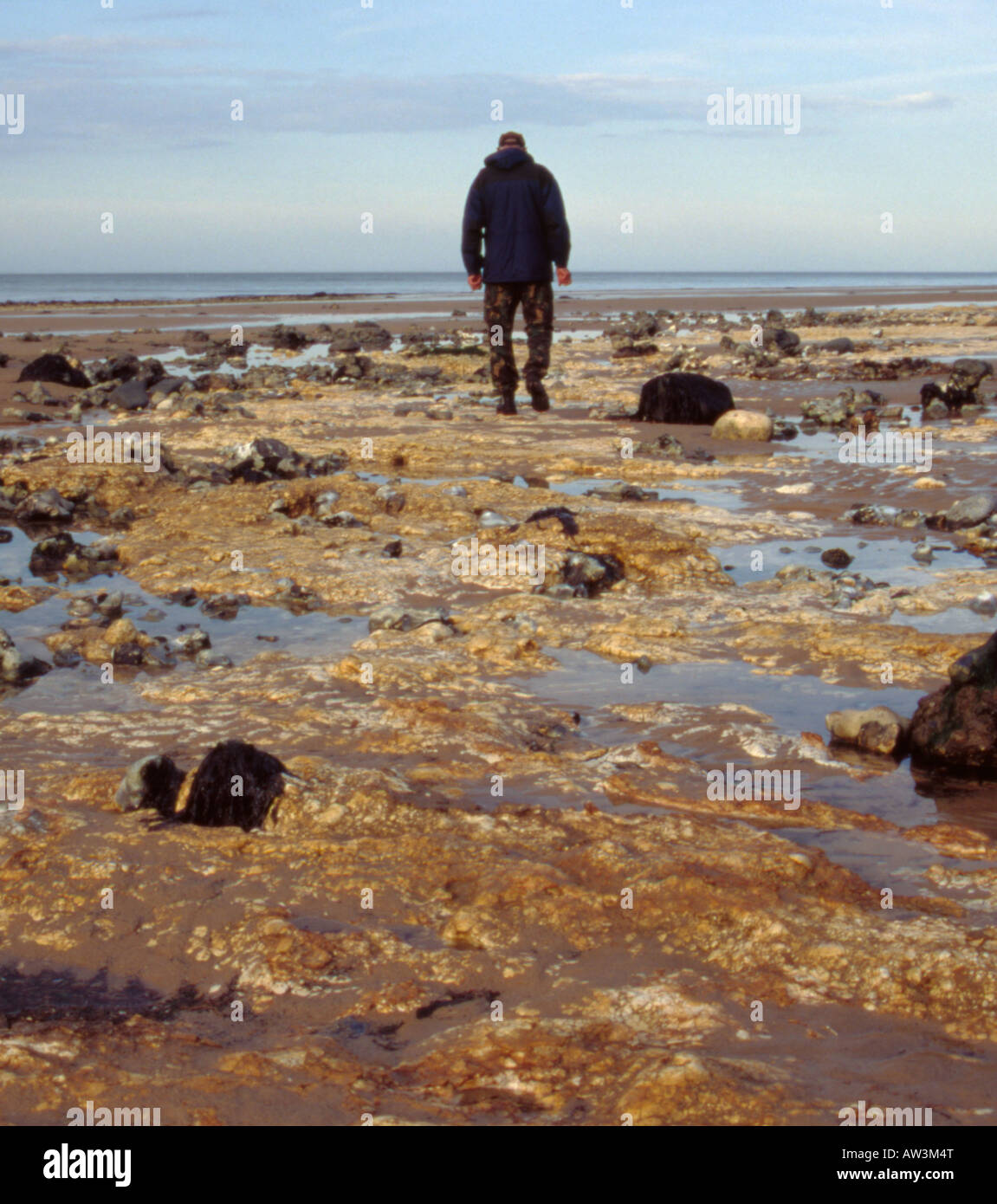 Mann zu Fuß auf einem Strand bei Ebbe, West Runton, Norfolk, England, UK. Stockfoto