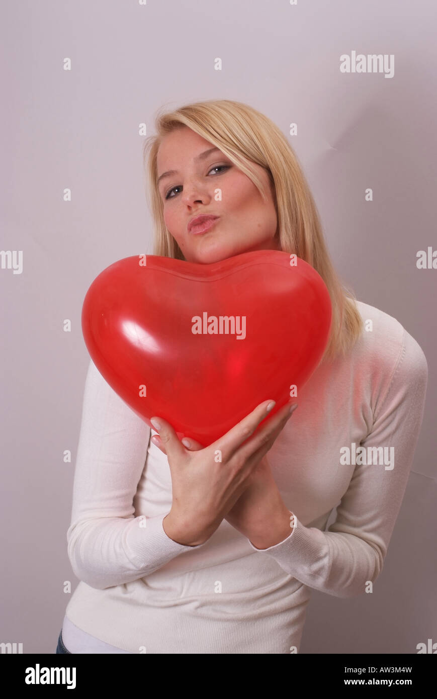 Junge schöne Frau mit roten Herzballon | Huebsche Junge blonde Frau Mit Rotem Herzluftballon Stockfoto