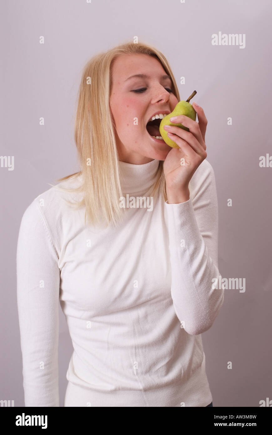 Blonde Frau essen eine Birne | Junge blonde Frau Isst Eine Birne Stockfoto