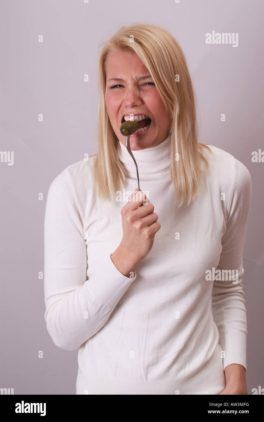 Blonde Junge Frau Beisst von Einer Essiggurke | Schöne junge Frau beißt in eine Gurke Stockfoto