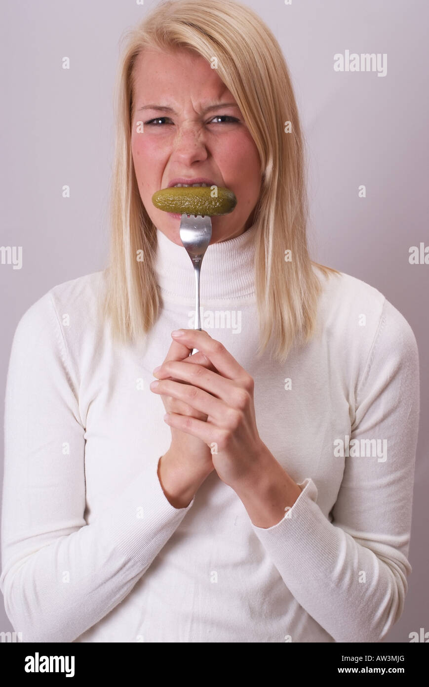 Frau isst eine Gurke | Frau Isst blond Eine Essiggurke Stockfoto