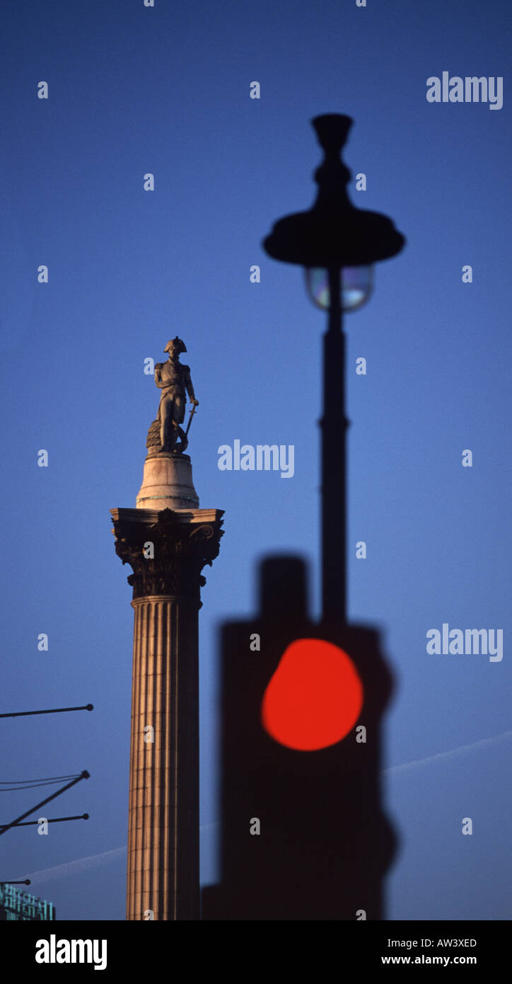 Die Nelsonsäule, Trafalgar Square, bei Sonnenuntergang mit roten Ampel und Lampost gesehen von Whitehall, London, England Stockfoto