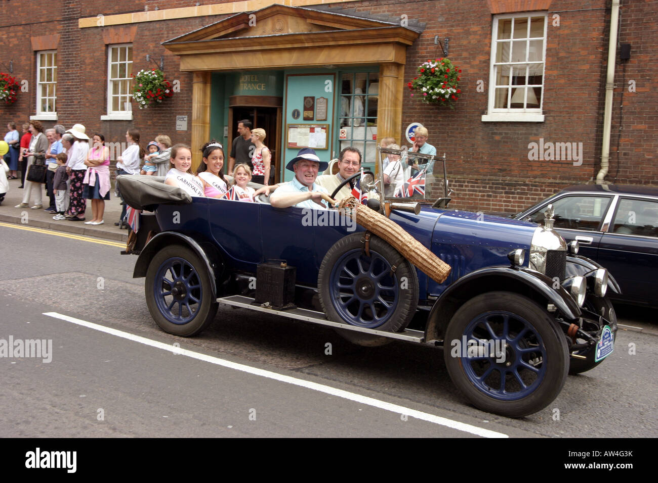 Die Karnevalskönigin und ihre Begleitpersonen im Oldtimerbus Bullnose Morris Auto, Newmarket Karneval, Suffolk England Stockfoto