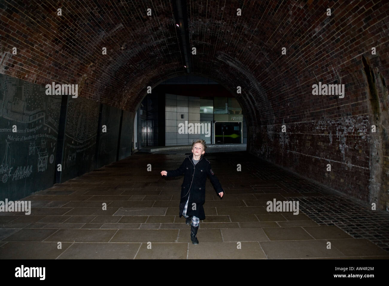 kleiner Junge läuft durch den dunklen Tunnel in london Stockfoto