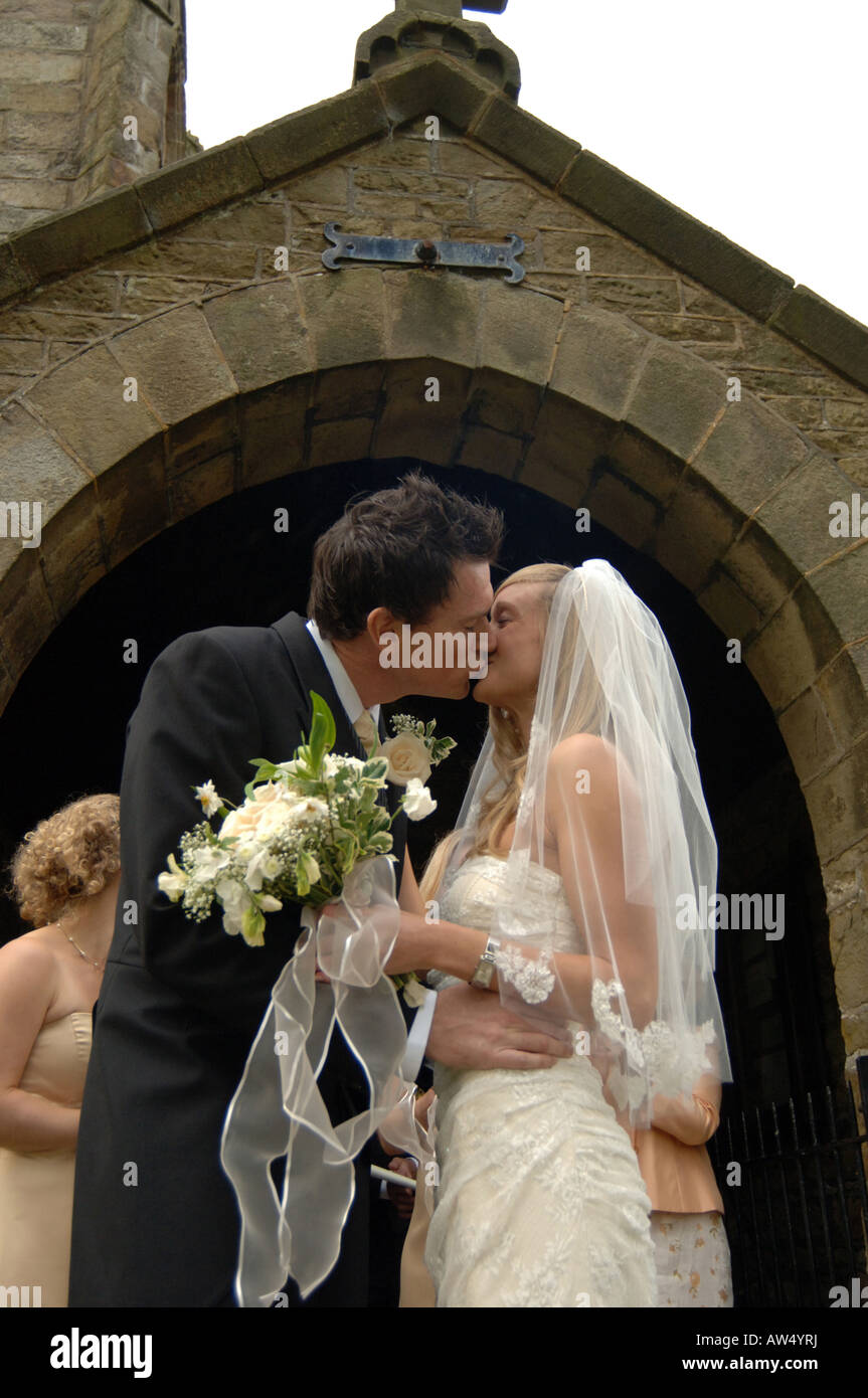 Ein paar Kuss vor der Kirche nach dem Aufstehen verheiratet Modell veröffentlicht Stockfoto