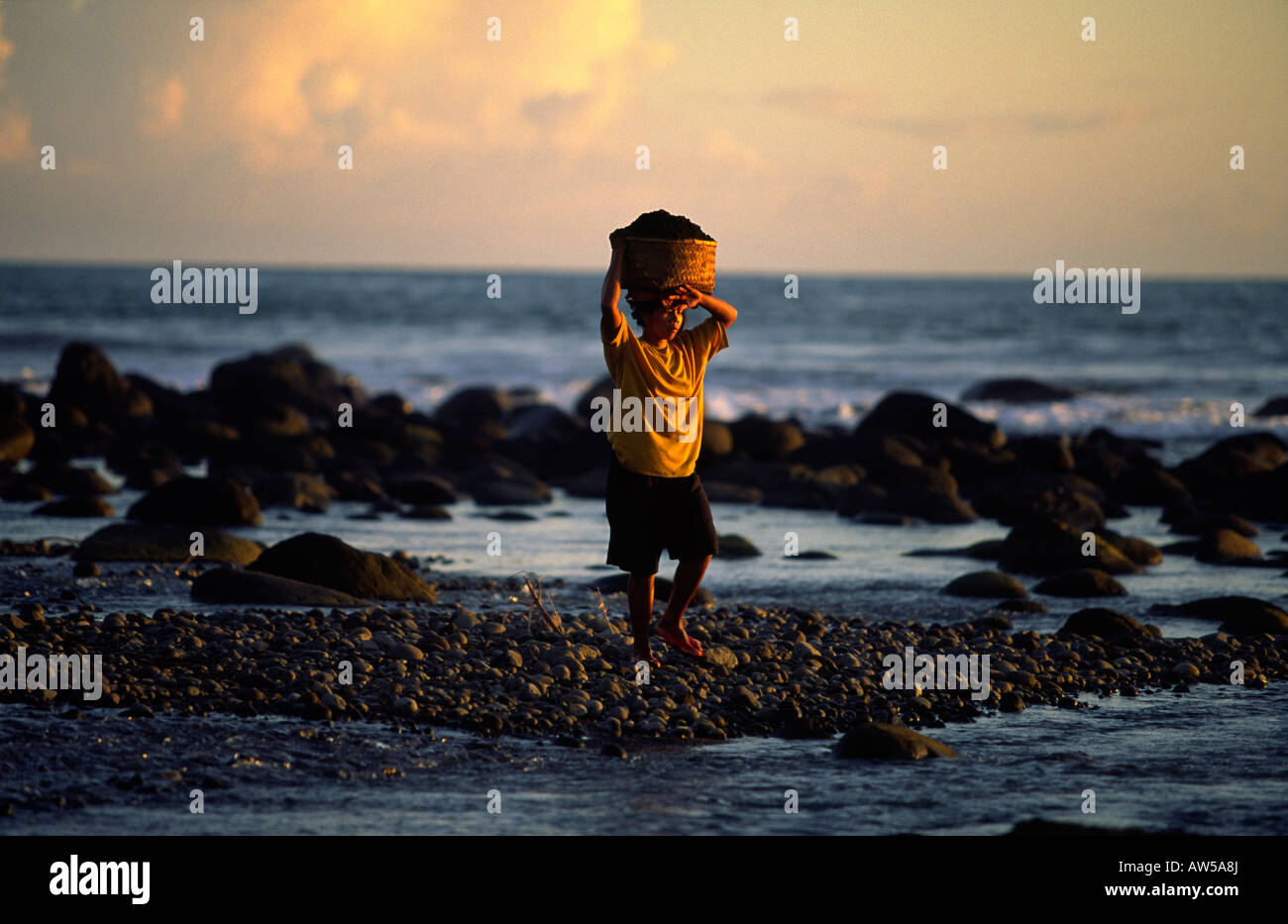 Indonesierin Korb voller Strand Kieselsteine Stockfoto