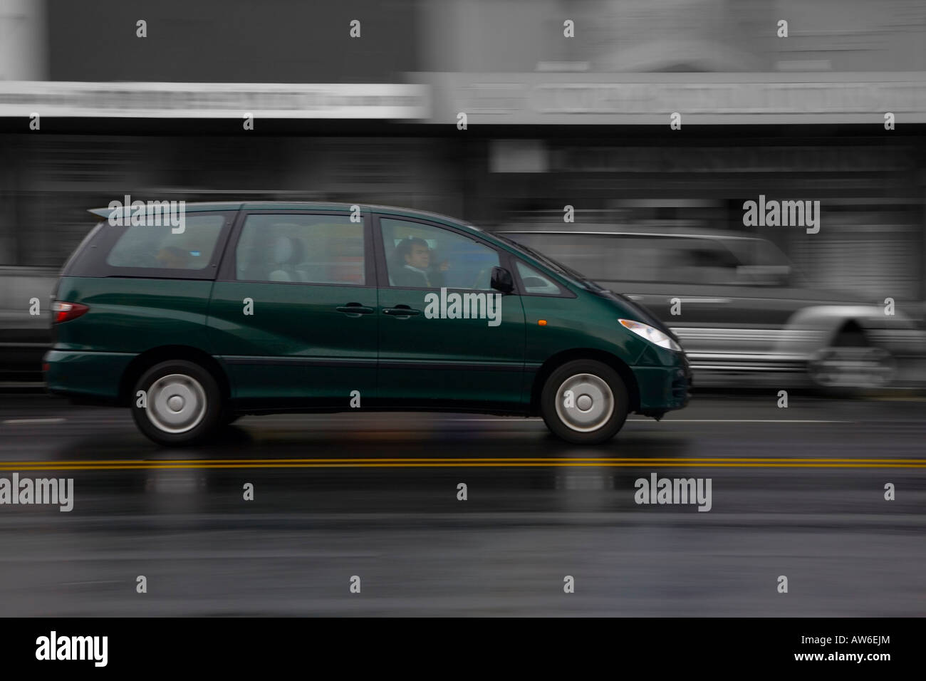 MPV in der Regen n Great North Road in Avondale, NZ mit unscharfen Rücken Boden von Gebäuden und 4 x 4 Stockfoto