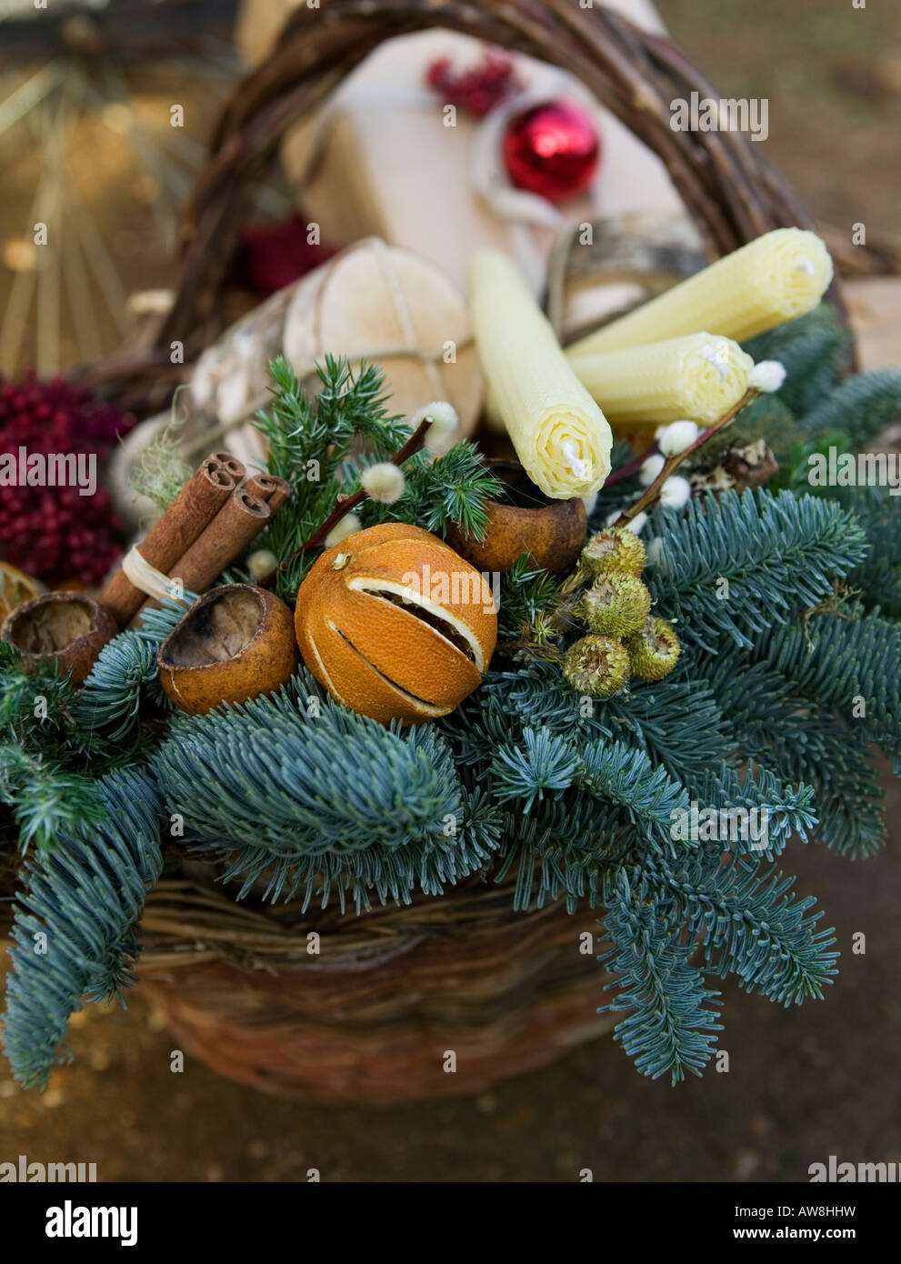 Dekorative festliche Korb mit Weihnachtsartikel wie Bienenwachskerzen, Tanne, Zimtstangen und Obst Stockfoto