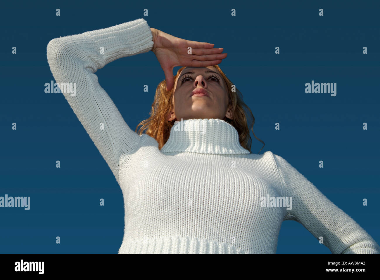 Woman Looking Out über einen offenen blauen Himmel mit der Hand ihre Augen vor der Sonne Abschirmung Stockfoto