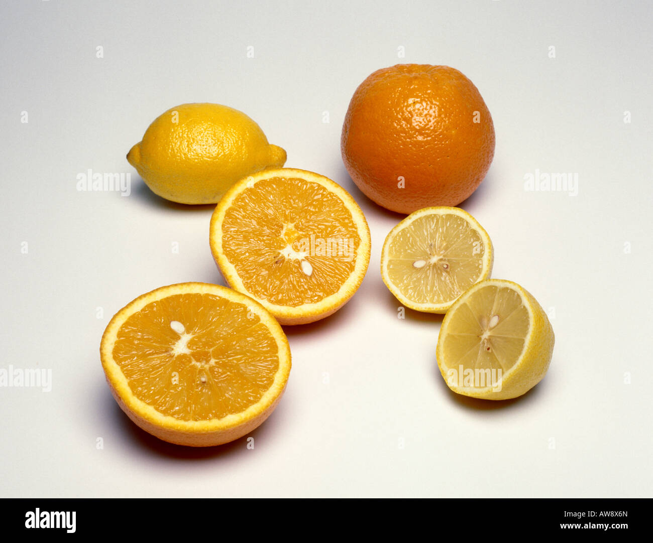 Eine ganze Orange und eine ganze Zitrone neben einer Zitrone halbieren und eine Orange in zwei Hälften geschnitten Stockfoto