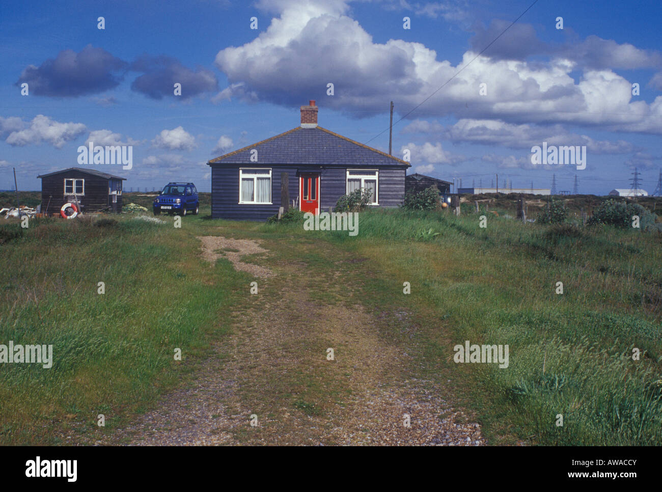 Schwarzen Bungalow bei Dungeness, in der Nähe von Kraftwerk mit Strommasten in Landschaft Stockfoto