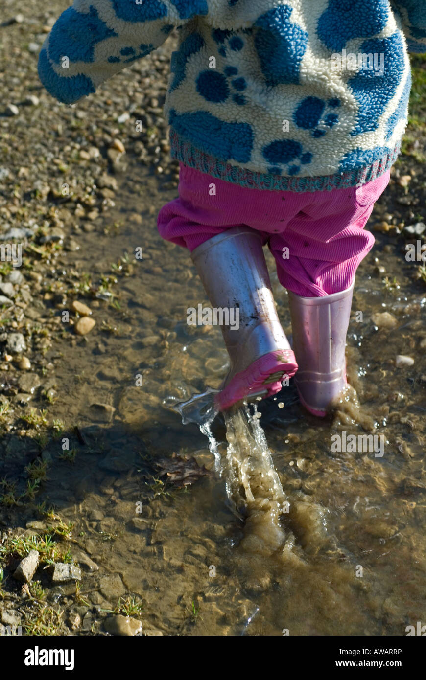 Bild eines Kindes in rosa Wellington boots in Pfützen planschen Stockfoto