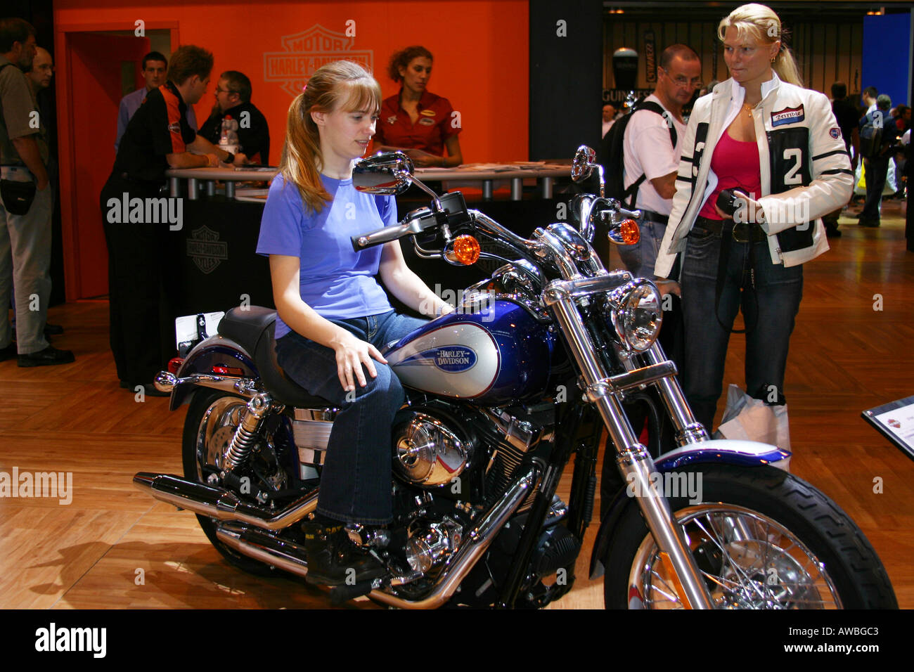 Mädchen sitzen auf Harley Davidson Motorrad während Freund Uhren bei der Motorrad-Show im NEC in Birmingham. Stockfoto