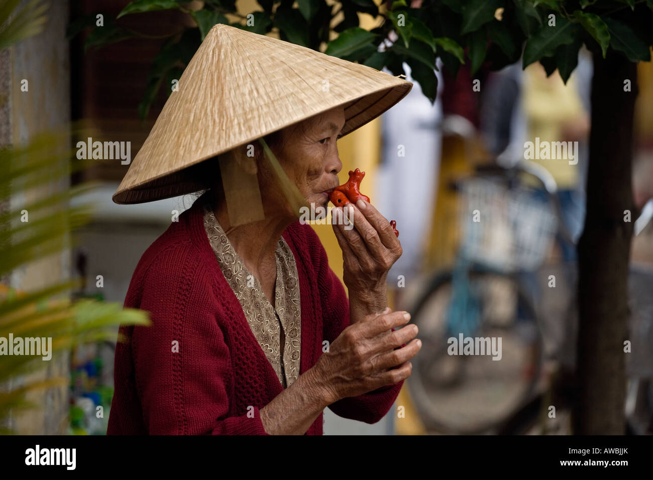 Eine ältere vietnamesische Frau spielt eine OKARINA auf den Straßen von HOI AN Zentralvietnam Stockfoto
