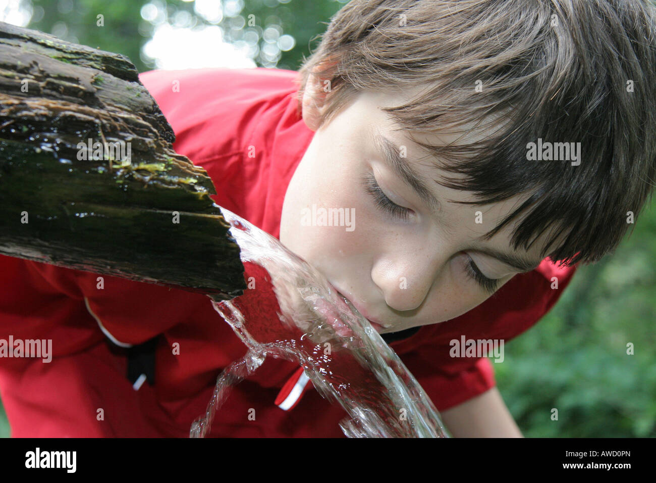 Kleiner Junge trinkt Wasser aus einem Brunnen Stockfoto