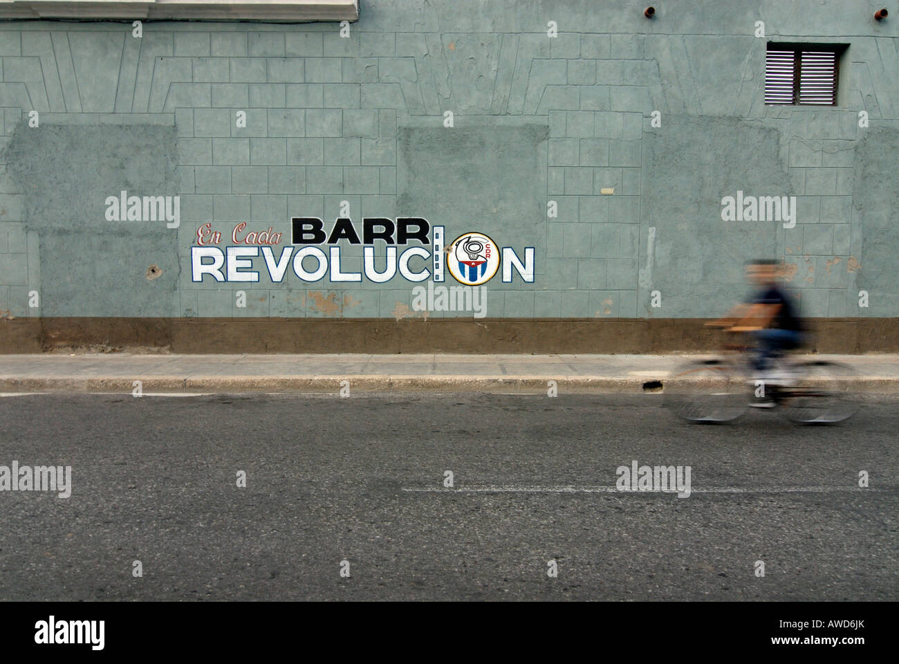 Mann auf Fahrrad sausen vorbei an politische Propaganda gemalt an der Wand in Cienfuegos, Kuba, Karibik, Amerika Stockfoto