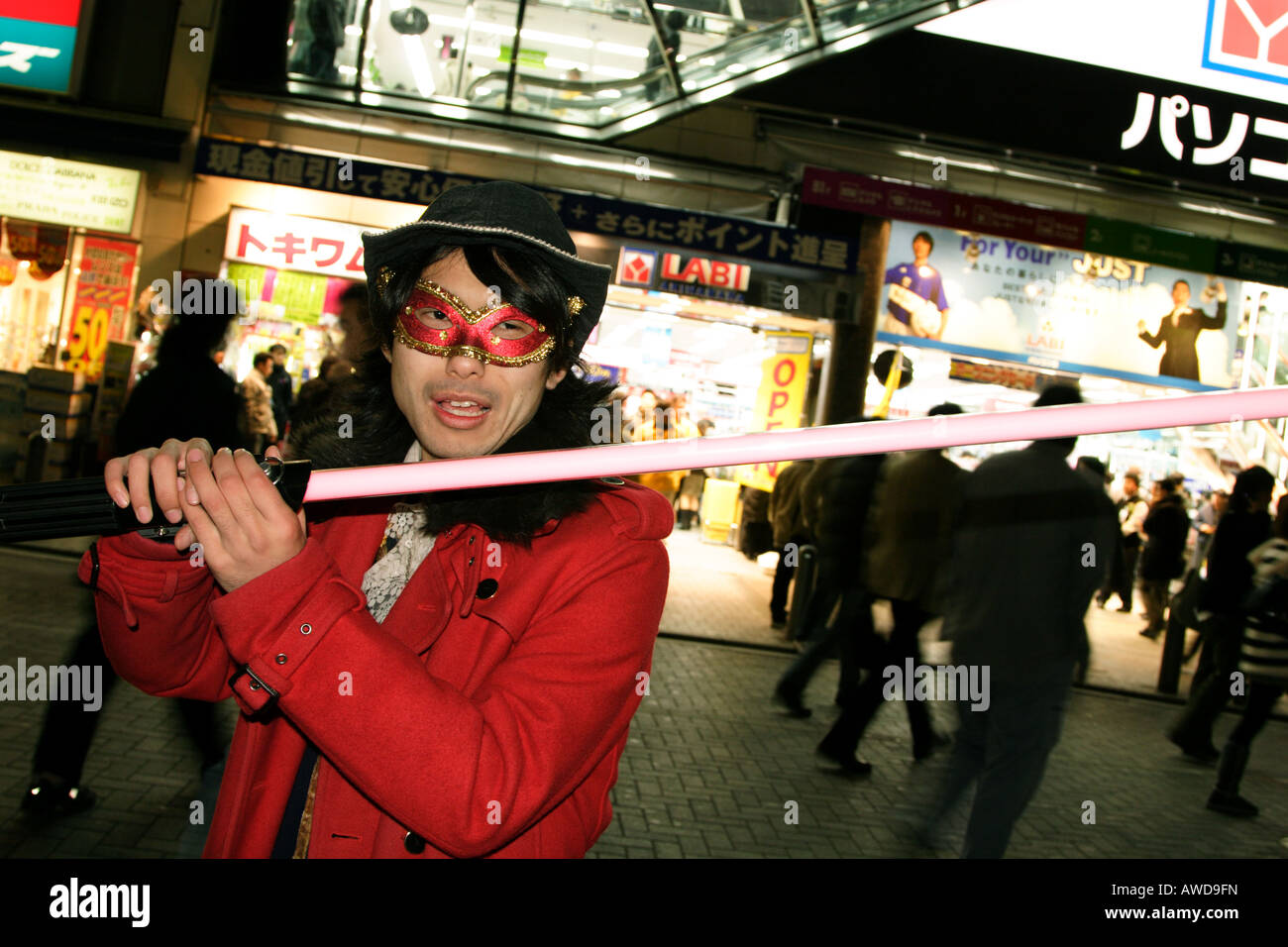 Ein junger Mann trägt eine rote Jacke und Maske hält eine "Lichtschwert" in Akihabara, Tokyo, Japan Stockfoto