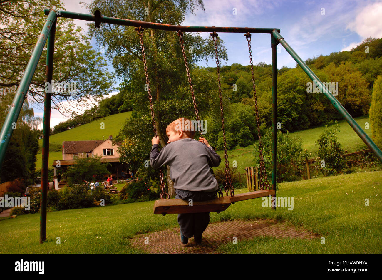 EIN KLEINER JUNGE SPIELT AUF EINER SCHAUKEL IM NEUEN INN IN WATERLEY UNTEN IN DER NÄHE VON DURSLEY GLOUCESTERSHIRE UK Stockfoto