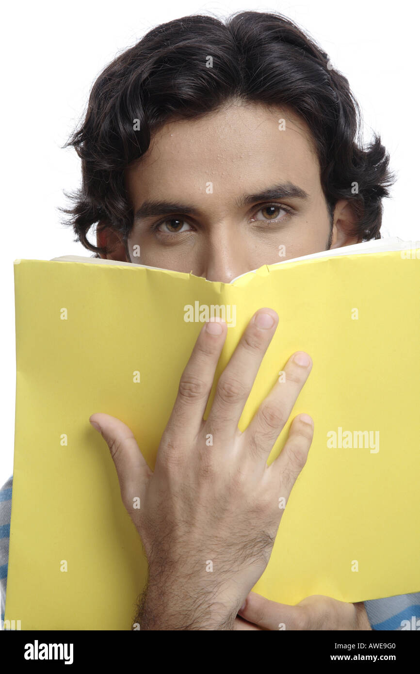 ANG200513 Teenager halten gelbes überdachte Buch vor sein Gesicht Herr 687T Stockfoto