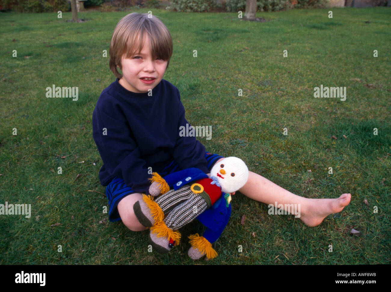 Junge hält gestrickt Puppe im Garten Surrey England Stockfoto