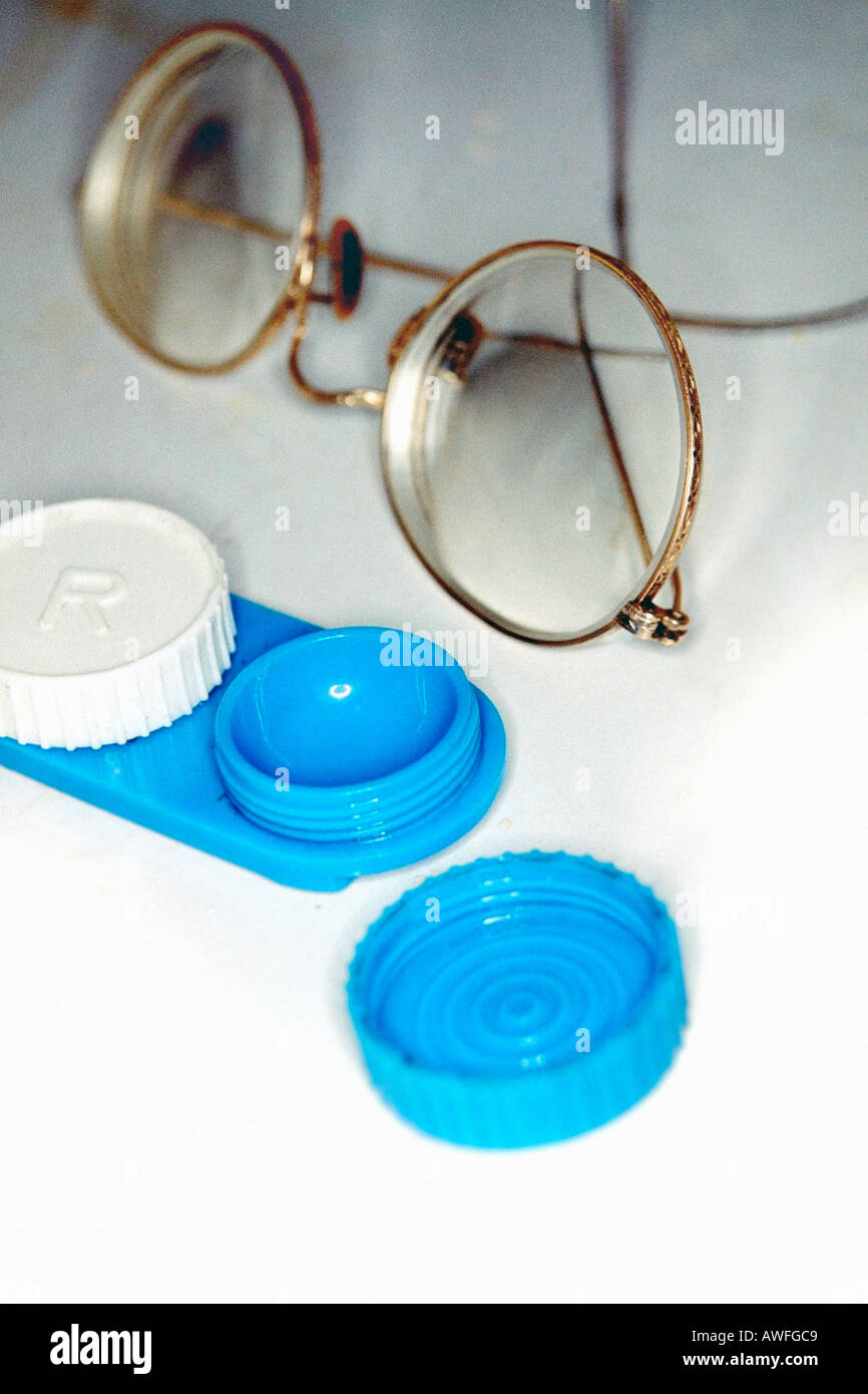 Stillleben mit ein paar getönten Metall gerahmten Golddraht umrandeten Brille und eine blaue Kontaktlinsenbehälter auf einem Waschbecken-Zähler Stockfoto